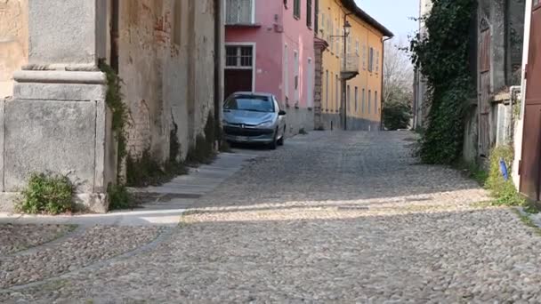 Costigliole d 'Asti, Piedmont, İtalya. Mart 2020. Tarihi merkezdeki bir şeritteki eğim görüntüleri: kaldırımlı cadde ve köydeki evlerin renkli cepheleri. Sokakta kimse yok.. — Stok video