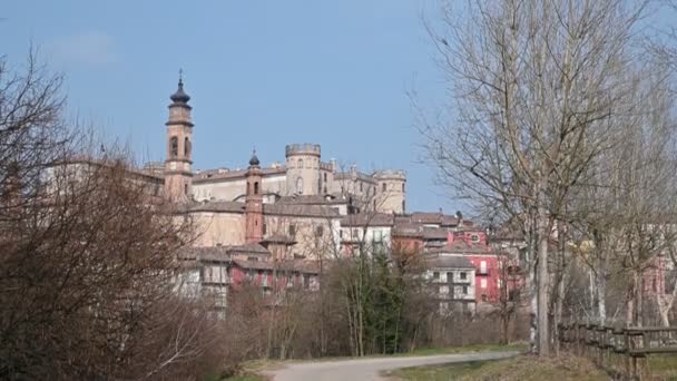 Costigliole d 'Asti, Piemonte, Italien. Mars 2020. Lutningsbilder precis utanför byn. När man blickar upp från gatan sticker det eleganta slottet med röda ytor ut.. — Stockvideo