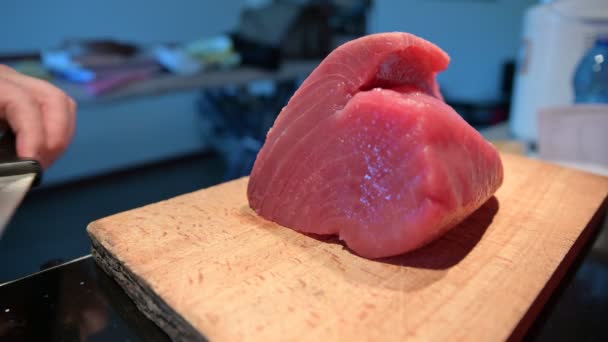 Sashimi için mavi yüzgeçli ton balığının hazırlanması: ahşap kesme tahtasının üzerinde büyük bir parça ton balığı, beyaz bir adamın eli yanına uzun bir bıçak bıçağı koyar.. — Stok video
