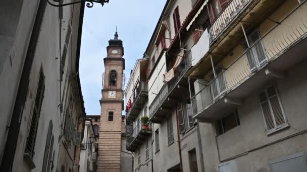 Costigliole d 'Asti, Piedmont, İtalya. Mart 2020. Kırmızı tuğlalı çan kulesinde durağan bir görüntü. Caddedeki evlerin perspektifi çan kulesine bakıyor.. — Stok video