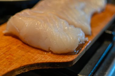 Tahta kesme tahtasına yerleştirilmiş morina filetosunun yakın çekim görüntüsü..