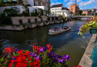 Gent, Belçika, Ağustos 2019. Kanallar turist tekneleriyle kesişiyor: şehre özel bir bakış açısı veriyorlar. Bankalar boyunca saksılar manzarayı hoş bir şekilde renklendiriyor. Güzel gün.