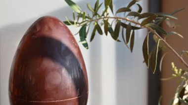 Koronavirüs salgını zamanındaki Paskalya 'nın kavramsal görüntüsü. Yanında zeytin dalı olan bir çikolata yumurtası. Kafkas erkek elleri yumurtaya mavi koruyucu bir maske taktı..