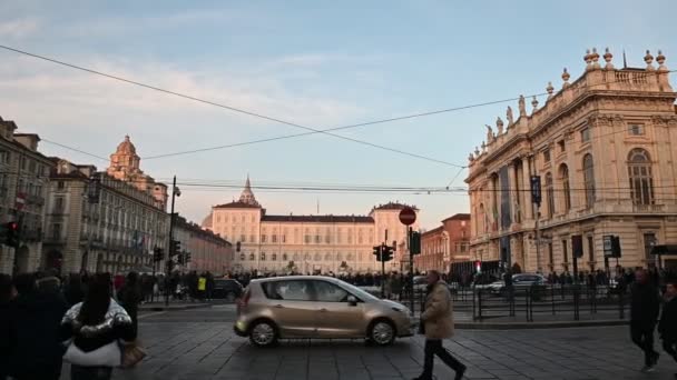 Turim, região do Piemonte. Itália, fevereiro de 2020. Filmagem com movimento pan na Piazza Castello em direção ao palácio real. O sol da tarde ilumina a fachada. Pessoas passeiam, passando carros — Vídeo de Stock