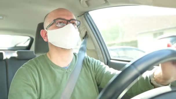 コロナウイルスパンデミック 白いマスクをした白人男性運転車の肖像 — ストック動画