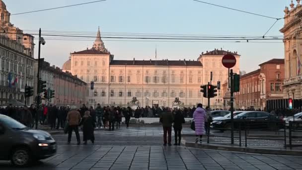 Turim, região do Piemonte. Itália, fevereiro de 2020. Filmagem com movimento de inclinação na Piazza Castello em direção ao palácio real. O sol da tarde ilumina a fachada. Pessoas passeiam, passando carros — Vídeo de Stock