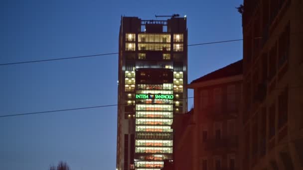 2020年2月イタリア・トリノのピードモント広場駅から撮影された夜の映像背景には、 Intesa-SanPaolo銀行の本社である超高層ビルがあります。緑の文字が強調表示され、ライトが点滅. — ストック動画