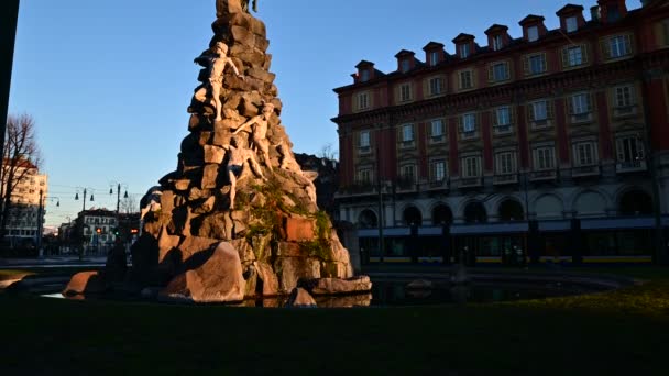 Turin, Piemonte-regionen. Italien, januari 2020. Piazza statuto, vid Frejus tunnel fontänen, bilder med lutning rörelse. Det varma morgonljuset lyser upp de vita statyerna, ovanpå den mörka ängeln. — Stockvideo