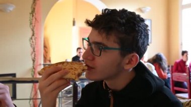 Ravenna, İtalya - Aralık 2019: Gözlüklü beyaz çocuk, turistler tarafından çok beğenilen bir İtalyan yemeği olan Romagna piadina 'yı yiyor. Jambon ve peynirin leziz dolgusunu görebilirsiniz..
