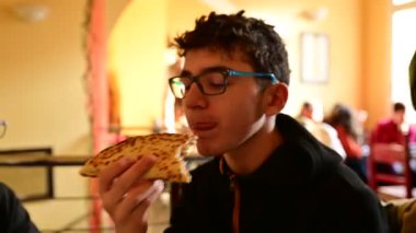 Ravenna, İtalya - Aralık 2019: Gözlüklü beyaz çocuk, turistler tarafından çok beğenilen bir İtalyan yemeği olan Romagna piadina 'yı yiyor. Jambon ve peynirin leziz dolgusunu görebilirsiniz..