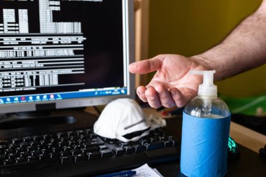 Coronavirus salgını zamanında evde bir iş. Klavyeye yerleştirilen maske, elleri sterilize etmek için sterilize edilmiş jel..