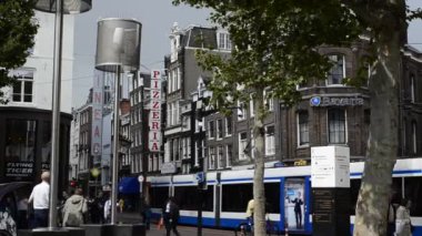 Amsterdam, Hollanda - Ağustos 2019 İnsanlar kavşağı geçiyor. Arka planda bir restoranın pizzacısı yazıyor. Beyaz ve mavi bir tramvay kavşağı geçiyor..