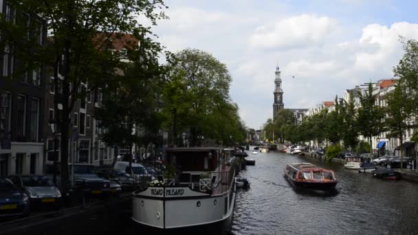 アムステルダム オランダ 2019年8月 魅惑的な運河の1つで見る 背景にあるヴェスターケルク教会の鐘楼がある観光船が通過しています — ストック動画
