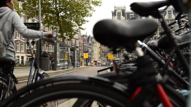 荷兰阿姆斯特丹 2019年8月 一个特殊的观点 从一辆停放的自行车模糊的车架和鞍座上 我们可以看到骑自行车的人走过自行车道 再往左边一点 电车停了 — 图库视频影像