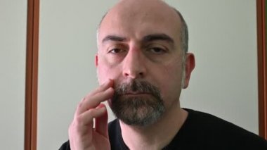 Koronavirüsten korunmak için koruyucu maske takan beyaz bir adamın portresi: maske çıkarıldığında, kenar ve elastik izler deride iz kalır..