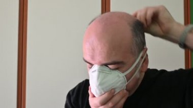 Koronavirüsten korunmak için koruyucu maske takan beyaz bir adamın portresi: maske çıkarıldığında, kenar ve elastik izler deride iz kalır..