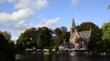 Bruges, Belçika - Ağustos 2019: Aşk Gölü olarak da bilinen büyüleyici Minnewater: restoran olarak kullanılan şato suya yansıyor. Ağaçlar yeşil bir çerçeve.