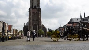 Delft, Hollanda - Ağustos 2019 eski kasaba meydanı, belediye binasına ve yeni kiliseye bakıyor. Sayısız kafe ve restoran, insanlar meydanda yürüyor. Çan kulesinde hareket var..