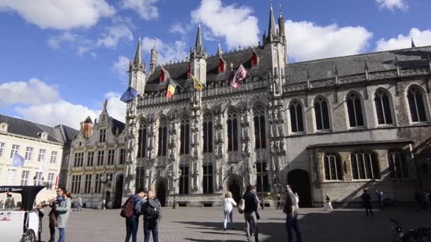 ベルギーのブルージュ 2019 魅力的な旧市街では ブルグは市庁舎広場です 旗がファサードに掲揚される 広場を横断する観光客 — ストック動画