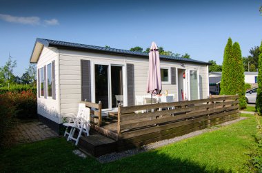 Netherlands, Zeeland - August, 2019: A nice campsite equipped with bungalows. Outside the house there is a small private garden, equipped with chairs and sun umbrella. clipart
