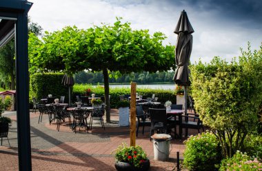 Hollanda, Zeeland bölgesi. Ağustos 2019. Restoranın göle bakan açık masaları var: masalar yeşillik ile çevrili ve manzaranın tadını çıkar.