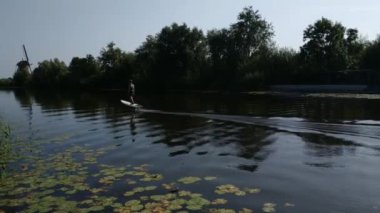 Zaanse Schans, Hollanda - Ağustos 2019: Kuzeydoğu Amsterdam Zaan Nehri üzerinde yer alan küçük bir topluluktur. Nehir kıyısındaki değirmenlerin manzarası parlak renkleriyle göze çarpıyor. Bulutlu bir gün.