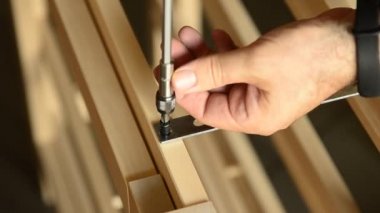 Tahtadaki elektrikli tornavidayla sabitlenmiş bir çift vidanın yakın plan çekimi..