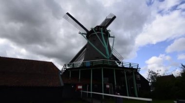 Zaanse Schans, Hollanda - Ağustos 2019: Kuzeydoğu Amsterdam Zaan Nehri üzerinde yer alan küçük bir topluluktur. Nehir kıyısındaki değirmenlerin manzarası parlak renkleriyle göze çarpıyor. Bulutlu bir gün.