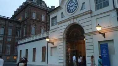 Piedmont, İtalya - Temmuz 2019: Piazza della β bblica sarayın girişi. Saat kulesine girin. İnsanlar akşamları serinliyor.