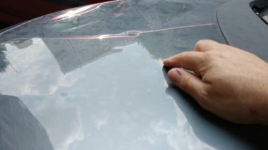 Dolu yüzünden arabanın kaputu hasar gördü. Gün ışığı, buz tanelerinin neden olduğu göçükleri vurguluyor.