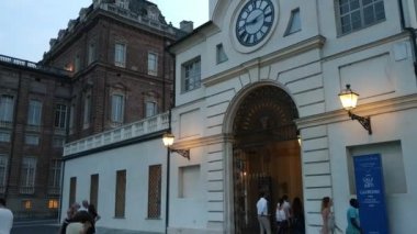 Piedmont, İtalya - Temmuz 2019: Piazza della β bblica sarayın girişi. Saat kulesine girin. İnsanlar akşamları serinliyor.