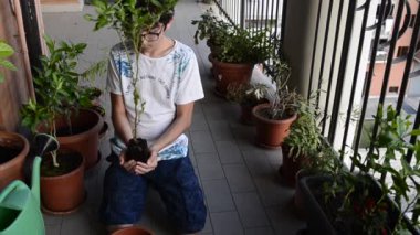 Kafkasyalı genç bir çocuk bir avuç dolusu toprağı az önce bir yabanmersini bitkisinin döküldüğü vazoya götürmek için nazikçe alıyor..