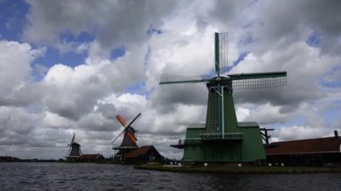 Zaanse Schans, Hollanda - Ağustos 2019: Kuzeydoğu Amsterdam Zaan Nehri üzerinde yer alan küçük bir topluluktur. Nehir kıyısındaki değirmenlerin manzarası parlak renkleriyle göze çarpıyor. Bulutlu bir gün.
