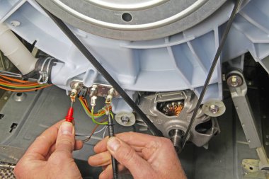 Süreklilik için test etmek için bir ısıtma elemanı üzerine multimetre prob tutan çamaşır makinesi cihaz tamir yerli elektrikli cihaz teknisyeni