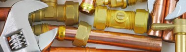 Plumber's pipes , fittings and wrenches  website banner    wide  random mixture of copper pipe, brass fittings  and wrenches ideal for use as a website header  background clipart