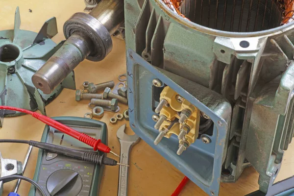 Three phase induction   motor bearing repair  A fitter/technician  checking motor windings resistance readings with a multimeter.