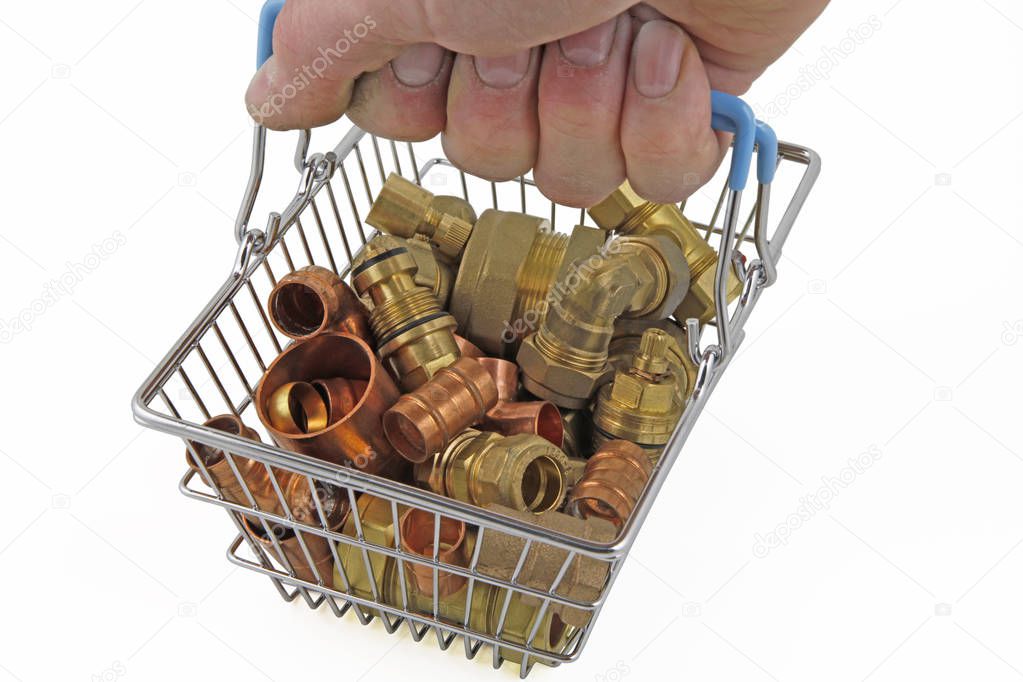 Plumbing  A hand holding a shopping basket containing copper and brass fittings on an isolated white background, 