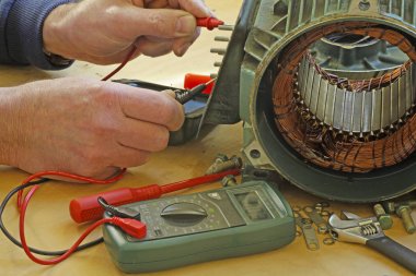 Üç fazlı endüksiyon motor taşıyan onarmak bir tesisatçı/teknisyen motor sargıları direnç okuma bir multimetre ile kontrol.