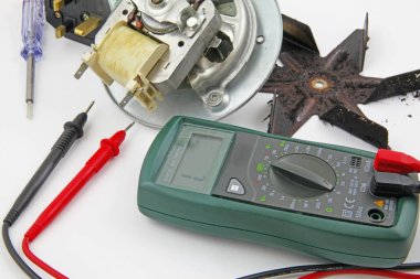 Süreklilik elektrik mühendisi beyaz bir arka plan üzerinde izole bir multi metre ile süreklilik bir fırın fan kontrol kontrol cihazı mühendis