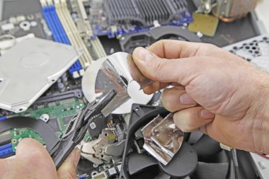 Bilgisayar diski imha - arka plan bilgisayar parçaları üzerinde bir sabit disk disk yok etmek için bir anahtar kullanan bir kişi 