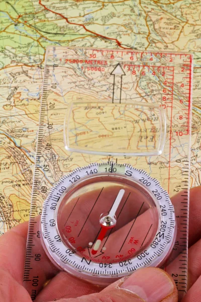 Compass and  map -  A hand holding a magnetic compass being lined up to walk on a magnetic bearing