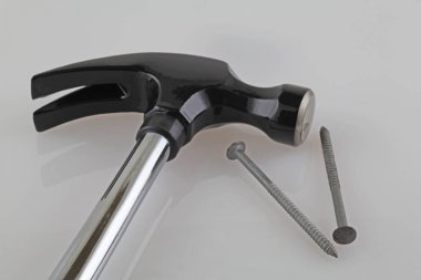 Marangoz aracı - beyaz yansıtıcı arka planda bir çekiç ve çivi bir plan görünümü