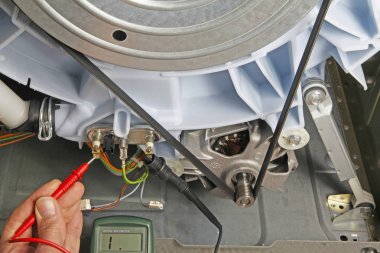 Süreklilik için test etmek için bir ısıtma elemanı üzerine multimetre prob tutan çamaşır makinesi cihaz tamir yerli elektrikli cihaz teknisyeni