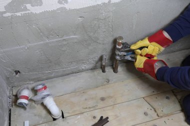 Tesisatçı iç tuvaletteki anahtarlarla boru tesisatını düzeltiyor.