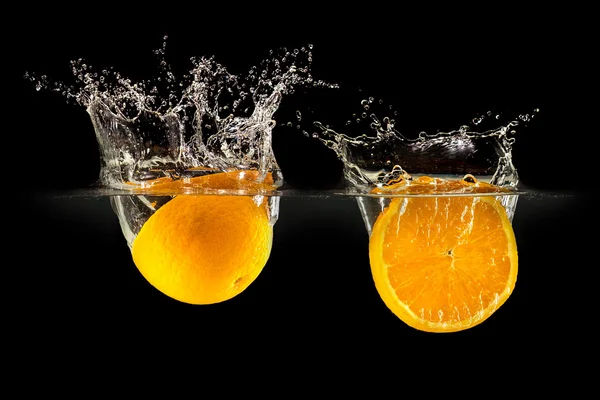Gruppe frischer Früchte fällt in Wasser mit Spritzer auf schwarzem Hintergrund — Stockfoto