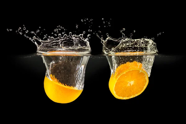 Group of fresh fruits falling in water with splash on black background — Stock Photo, Image