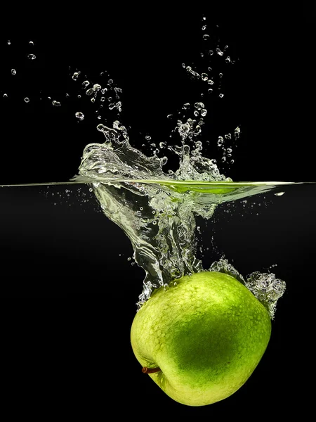 Grönt äpple som faller i vattnet på svart bakgrund — Stockfoto