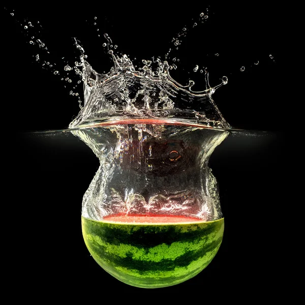 Frische Melone fällt in Wasser mit Spritzer auf schwarzem Hintergrund — Stockfoto