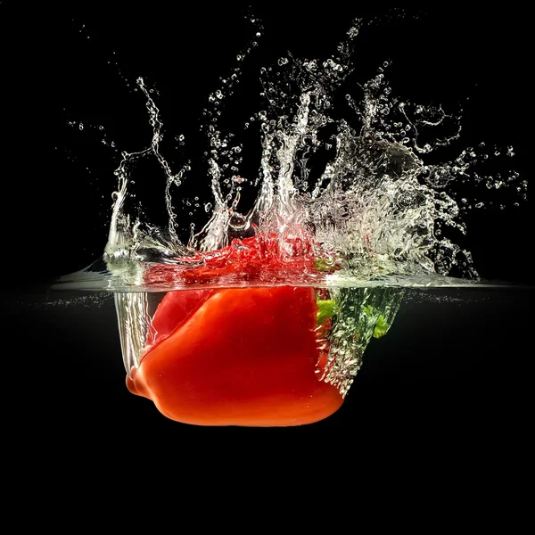 Pimenta vermelha caindo na água com respingo no fundo preto — Fotografia de Stock