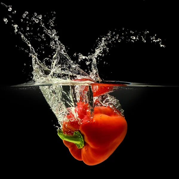 Peperoncino rosso che cade in acqua con spruzzata su fondo nero — Foto Stock